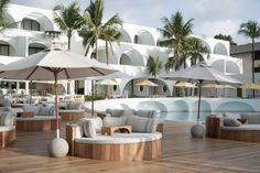 an outdoor seating area with umbrellas and chairs next to a swimming pool in front of a hotel