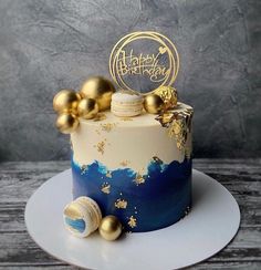 a blue and white cake with gold decorations on it's top, sitting on a plate