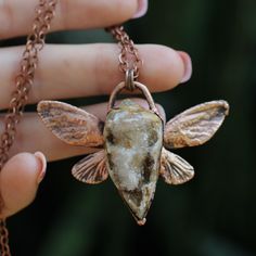 a person holding a piece of jewelry in their hand with the image of a bee on it