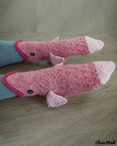 two knitted pink fish sitting on top of a wooden floor