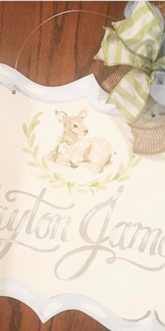 a white sign with a baby's name and a deer on it sitting on top of a wooden floor