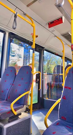 the inside of a bus with blue seats and yellow railings on both sides,