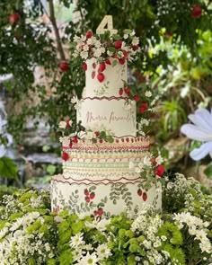 a three tiered cake with flowers and berries on it is surrounded by greenery