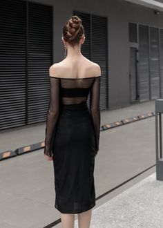 a woman in a black dress is walking down the street with her back to the camera