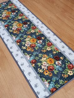 a table runner with flowers on it sitting on the floor next to a wood floor