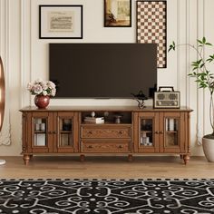 a living room with a large television on top of a wooden entertainment center next to a black and white rug