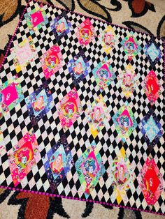 a black and white checkerboard quilt with pink, blue, yellow, green, red, orange, and purple designs on it