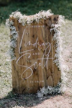 a wooden sign with white flowers and greenery on it that says, lindsey and scott