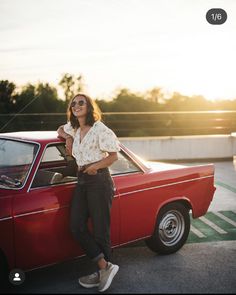 a woman standing next to a red car