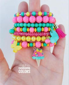 a hand holding a stack of bracelets with charms on it's sides and an ice cream cone in the middle