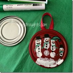 the paper plate has snowmen on it and is next to markers, marker pens, and an ornament