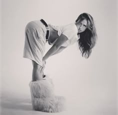 a woman in white shirt and furry boots posing for a black and white photo with long hair