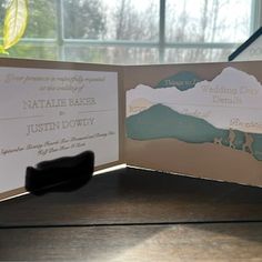 an open wedding card with mountains on it