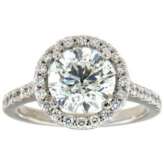 a white gold ring with an oval cut diamond surrounded by round brilliant pave diamonds