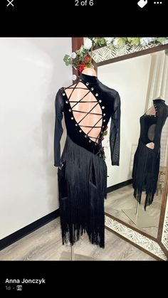 the back of a black dress with fringes on it and a mirror behind it