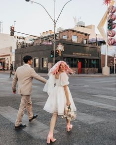 a bride and groom crossing the street holding hands