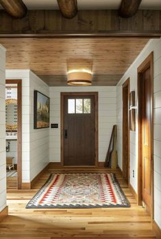 an entryway with wood paneling and a rug on the floor in front of it