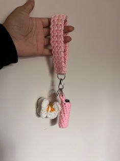 a hand holding a pink crochet keychain with two keys attached to it