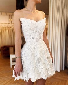 a woman in a short white dress is posing for the camera