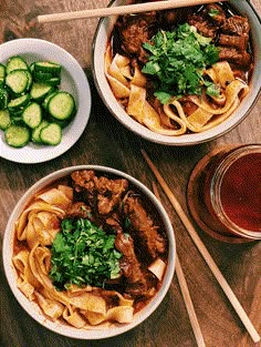 two bowls of food with chopsticks next to each other on a wooden table