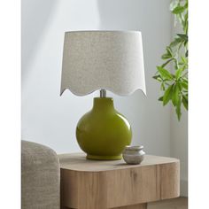 a green lamp sitting on top of a wooden table