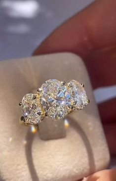 three stone diamond ring being held by someone's hand