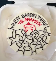 a white cake with red writing on it sitting in a plastic container filled with paper