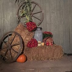 a hay bale filled with fruits and vegetables sitting next to a wheel on the ground