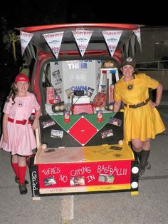 two girls in costumes standing next to a baseball machine