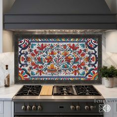 a stove top oven sitting under a colorful tile backsplash