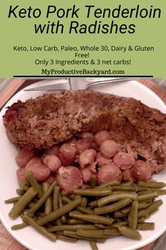 a white plate topped with meat and beans next to green beans on a wooden table