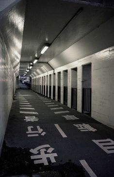 an empty hallway with chinese characters painted on the floor and in between two walls, there is a row of white doors