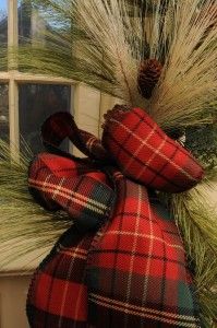 a red and black plaid bow on a window sill with grass in the foreground