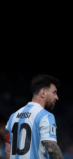 a man with tattoos on his arm standing in front of a soccer ball and wearing a jersey