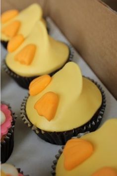 cupcakes with yellow frosting and orange icing on top in a box