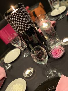 the table is set with wine glasses, plates and candles