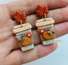 two small clay pumpkins are sitting on top of each other in front of a person's hand