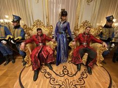 three men and two women sitting on gold chairs