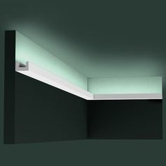 an empty room with black walls and green lighting on the ceiling is lit by recessed lights