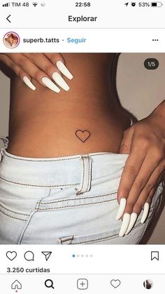 a woman's stomach with white nails and a heart tattoo on her left side