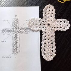 a crocheted cross sitting on top of a piece of paper