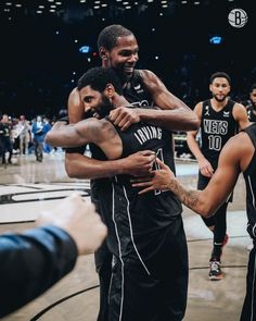 two basketball players hugging each other in the middle of a court with people around them