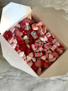 a box filled with lots of heart shaped candies on top of a white table