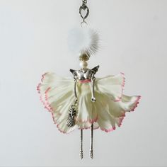 a white and pink angel ornament hanging from a chain