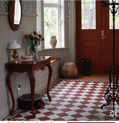 a red and white checkered floor in front of a wooden table with vases on it