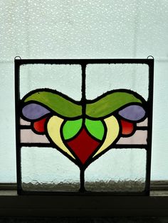 a stained glass window with an abstract design in the center and bottom section, on a white wall