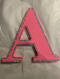 the letter a is made out of pink plastic and has lots of diamonds on it