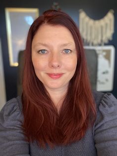 a woman with red hair and blue eyes posing for a photo in front of a mirror