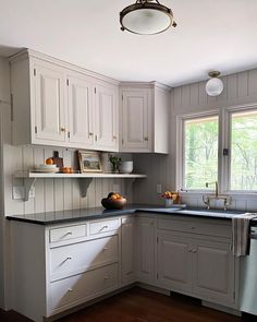 a kitchen with white cabinets and black counter tops in front of a large open window