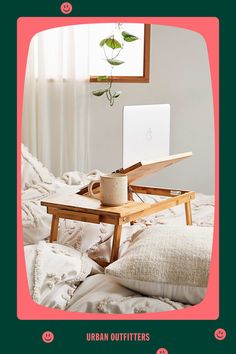 an open laptop computer sitting on top of a wooden table next to a white pillow